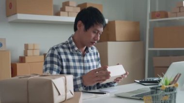 Çevrimiçi iş sahibi teslimattan önce paketlerin geçerliliğini kontrol ediyor. Mal sahibi sipariş listesini ve envanteri kontrol etmek için ürün kodlarını bir kitaba yazıyor. Nakliye yönetimi kavramları.