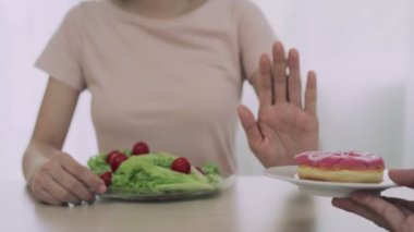 Kadınlar sağlıklı olmak için doğru yiyeceği seçiyorlar. Kadınlar oruç tutuyor. Diyet yemek ve abur cubur arasında karşılaştırma seçenekleri. ağırlık ölçümü, dijital ölçekler, kilo kaybı.
