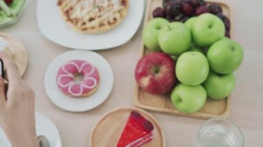 Kafe konsepti için yemek fotoğrafı çekin. Kadınlar yemek yemeden önce cep telefonlarını kullanır ve internete yükler. Öğle yemeği iştah açıcı görünüyor.. 