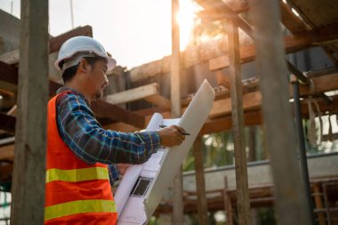 Müteahhit yeni evin taslak çizimini gözden geçirdi. Mühendisler inşaat detaylarını gerçek alandaki çizim karşılaştırmalarında okuyorlar. İnşaat mühendisi ve müfettiş kavramı
