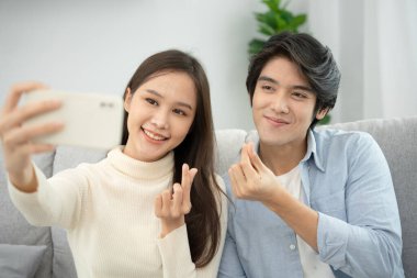 Asyalı çiftler yeni evlerinin tadını çıkarıyor ve birlikte selfie çekiyorlar. Evlendikten sonra genç bir karı koca. Ailede mutluluk, gülümseme ve kahkaha.