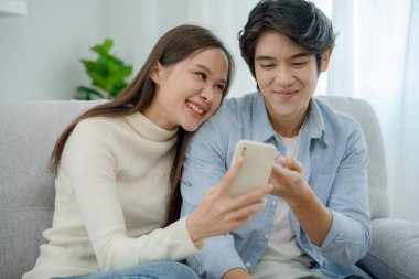 Asyalı çiftler yeni akıllı telefonların ve online filmlerin tadını çıkarıyorlar. Evlendikten sonra genç karı koca. Ailede mutluluk, gülümseme ve kahkaha.