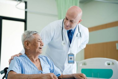 Doktor konuşur ve yaşlı erkek hastaları teşvik eder. Profesyonel doktor, tekerlekli sandalyedeki yaşlılara fiziksel muayeneyi açıklar ve danışır. Sağlık ve bakım, klinik, hastane