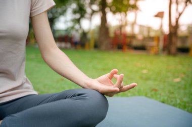 Genç sıska kadın parkta yoga yapıyor. Kız sabahları egzersiz yapıyor. denge, meditasyon, rahatlama, sağlıklı yaşam tarzı konsepti