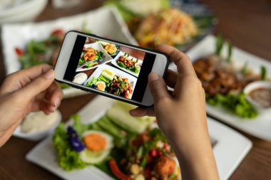 Kadın eli restorandaki yemek masasında yemek fotoğrafı çekmek için bir cep telefonu kullanıyor. Cep telefonu kavramlı fotoğrafçılık