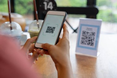 Kadınların elleri yemek menüsünü seçmek için QR kodunu tarıyor. İndirim için tarama yap ya da yiyecek için ödeme yap. Para transferi için telefon kullanma ya da nakit olmadan internet üzerinden para ödeme kavramı..