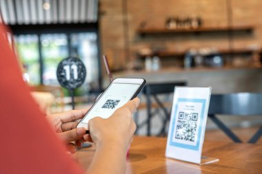Kadınların elleri yemek menüsünü seçmek için QR kodunu tarıyor. İndirim için tarama yap ya da yiyecek için ödeme yap. Para transferi için telefon kullanma ya da nakit olmadan internet üzerinden para ödeme kavramı..
