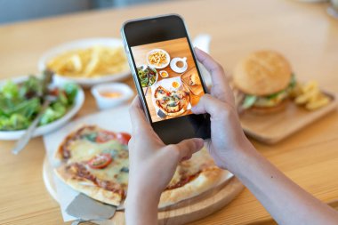 İtalyan yemeği. Restoran sahibi bir web sitesine yüklemek için masada akıllı bir telefonla yemeğin resmini çeker. Çevrimiçi yemek teslimatı ve sipariş servisi