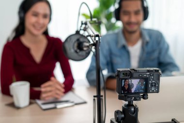 Asyalı radyo sunucusu Podcast stüdyoda. Bir erkek ve kadın konuşmacı internet üzerinden ev izleyicisiyle canlı olarak konuşuyor