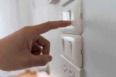 Elektrik tasarrufu, enerji tasarrufu ve çevre korumasından tasarruf edin. Işığı kapatmak için bir adamın parmağı düğmeye basar. Elektriğin ekonomik kullanımı