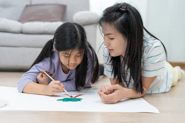 Mother teaches child to paint and paint in the living room. Good times together of single moms. Learn the arts and be together for a happy time.