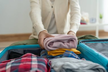 Tatil gezileri için seyahat çantaları. Genç bir kadın valizine koymak için giysilerini ve kişisel eşyalarını hazırlıyor. Yolculuktan önce bavullarınızı toplayın.