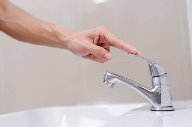 Banyodaki musluk ve akan su. Suyu kapatan ve çevreyi koruyan bir adam. dünya çevre günü