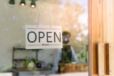 İş yeri sahibi, koronavirüs salgını sırasında karantinadan sonra küçük bir kafenin yeniden açılması için işaret verdi. Elinde tabela tutan adam açık yazıyor. Küçük kamu işletmeleri, restoran sahipleri, dükkan açmak için reklam panoları.