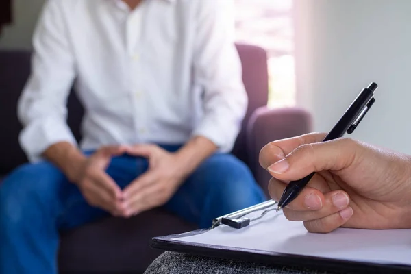 The psychologist talks to the patient and takes notes on the treatment. The patient is addicted to drugs, is stressed and frustrated with life problems.