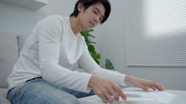 Asyalı adamlar fatura bilgilerini tekrar kontrol ediyor ve cep telefonu tarama kodlarını paralı olarak kullanıyorlar. Erkekler ödeme için evde kalarak ifadelerini tekrar kontrol ederler. Cep telefonuyla ödeme için tarama kavramı.