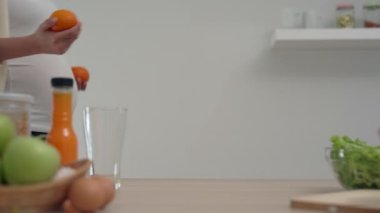 Hamile bir kadın mutlu bir şekilde mutfak odasına portakal atar. Hamile kadınlar doğmamış çocuğu beslemek için portakal suyu yapmaya hazırlanırlar..
