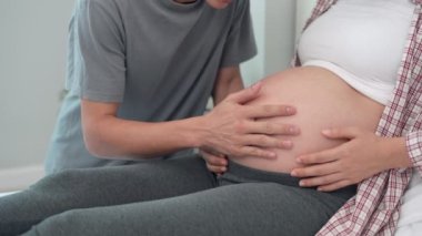 Baba, elini bebeğin aktivitesi için kullanıyor. Koca doğmamış kızının sesine dikkatle dokundu ve mutlu bir şekilde gülümsedi. Aile kavramı.