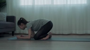 Güzel bir Asyalı kadın yoga yapar ve evde dinlenir. Bir kadın karnını rahatlatır ve kaslarını güçlendirir. Yoga konseptine göre sağlıklı ve eğlenceli..