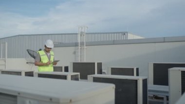 Kayıt için yürüyen bakım mühendisi fabrikanın çatısındaki havalandırma sistemi. Müfettiş Mühendis, günlük kayıt durumu. Teknoloji Mühendisi konsepti.