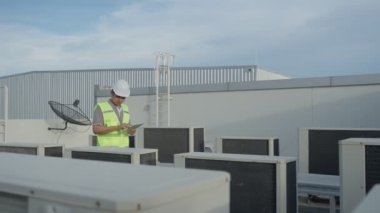 Kayıt için yürüyen bakım mühendisi fabrikanın çatısındaki havalandırma sistemi. Müfettiş Mühendis, günlük kayıt durumu. Teknoloji Mühendisi konsepti.