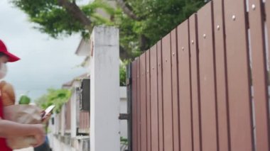 Kadın cep telefonu siparişini onayla. Teslimatçı başvuru sistemi üzerinden adresi doğruladı. Teslimatçı kapıya bir maske koydu..