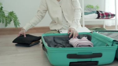 Bir kadın seyahat için bavuldan kıyafet seçer ve tam doz aşı aldıktan ve pasaport aşısını aldıktan sonra seyahat çantasına devam eder. Tatil seyahati kavramı.