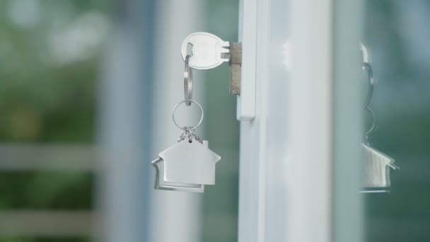 家をロック解除するための家主の家の鍵がドアに接続されています 賃貸と販売のための中古の家 キーチェーンが風に吹かれてる 新しい家 投資のための家主 — ストック動画