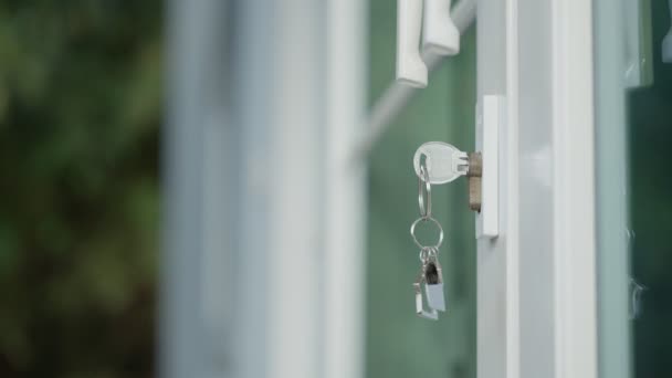 家をロック解除するための家主の家の鍵がドアに接続されています 賃貸と販売のための中古の家 キーチェーンが風に吹かれてる 新しい家 投資のための家主 — ストック動画