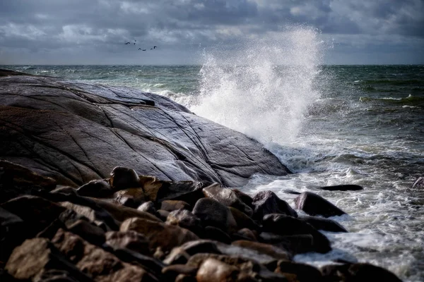 Deniz kenarında rüzgarlı. Büyük bir dalga kayalara çarpıyor..