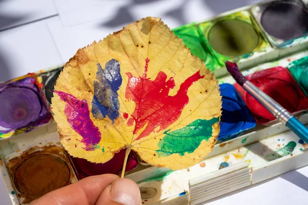 Autumn crafts with paint and leaves in kindergarten