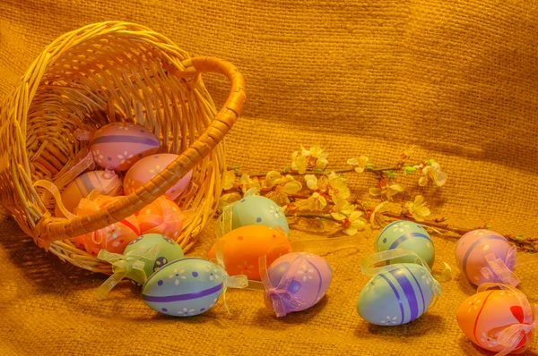 Рассеянные пасхальные яйца, корзинки и абрикосовые цветы на фоне мешковины — стоковое фото