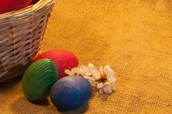 Huevos de Pascua y una cesta sobre fondo de saco —  Fotos de Stock