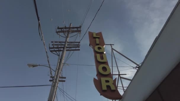 Licor tienda flecha signo con cielos azules electricidad postes y avión volando por — Vídeos de Stock