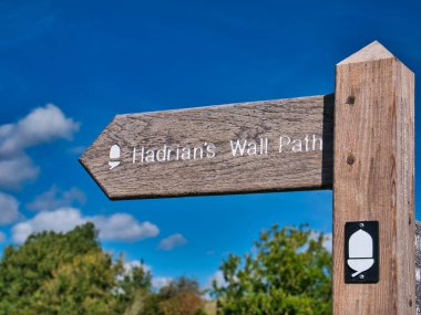 A weathered, wooden signpost points the way of Hadrian's Wall Path, a National Trail in the UK. Taken on a sunny day with a blue sky. clipart