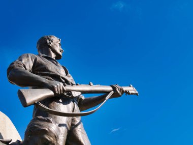 Sör William Goscombe John RA 'nın Port Sunlight War Memorial' ından tüfeği olan bir askerin bronz heykeli. Güneşli bir günde, mavi bir gökyüzünde çekildi..