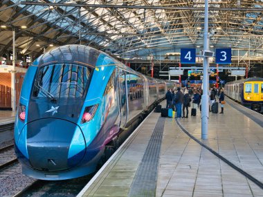 Passengers wait to board a TransPennine Express at Lime Street Station in Liverpool, UK. The train is destined for Newcastle in north east England. clipart
