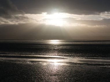 Kuzey Batı İngiltere 'de Wirral' deki West Kirby 'de, Dee Estuary' nin çamurlu düzlüklerinde güneş doğuyor. Kuzeybatı Galler kıyıları uzakta görünüyor. Kışın çekildi..