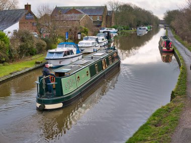 İngiltere 'nin Lancashire kentinde, Garstang, Lancashire' daki Moss Lane Köprüsü yakınlarındaki Lancaster Kanalı 'ndan geçen yeşil bir dar kayık (Gregory' s Girl). Sakin, bulutlu bir kış gününde çekilen.