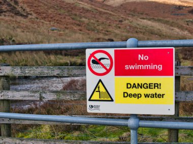 Çelik bariyerlerdeki sarı ve kırmızı Birleşmiş Hizmetler tabelaları Bowland, Lancashire, İngiltere ve İngiltere 'deki Whitendale Nehri' nin yukarısındaki havuzda yüzmeyi yasaklıyor.
