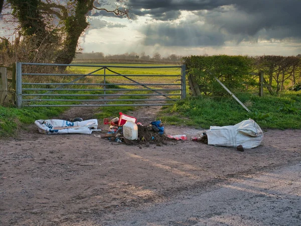 Kışın bir tarlanın girişine yasa dışı olarak atılmış ev atıkları. İngiltere 'nin kuzey batısında çekildi..