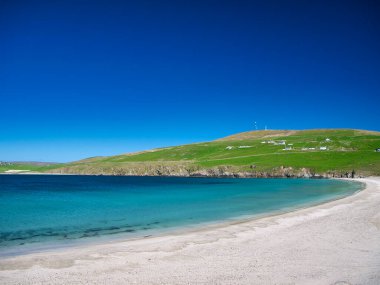 Güney Shetland, İngiltere 'deki Spiggie Sahili' nin (Scousburgh Sahili) beyaz kum ve turkuaz suyu. Güneşli bir günde çekilen açık mavi gökyüzü.