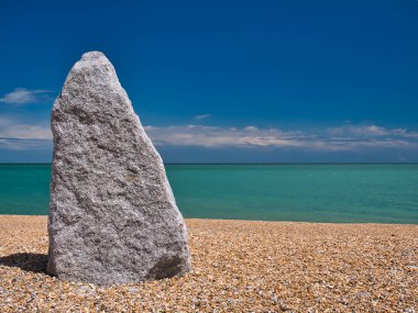 Walmer, Deal, Kent, İngiltere 'deki tağ plajında uzun, 2 metrelik, gri, dik duran bir taş. Güneşli bir günde mavi gökyüzü ve turkuaz bir denizde çekildi..