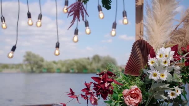 漂亮的婚纱装饰着鲜花 在湖底装饰有灯泡的婚礼拱门 — 图库视频影像