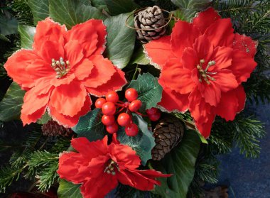 Yapay kırmızı çiçekler ve mezardaki çam kozalakları