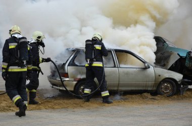 Firefighters next to a smoking car