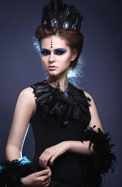 Gothic girl with a crown and a necklace of feathers and creative makeup. — Stock Photo, Image