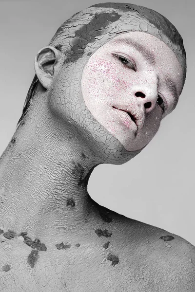 Young man with art creative make-up with mud on his face. Cosmetic mask. Stock Image