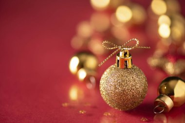 Altın renginde Noel ağacı topu, kırmızı arka planda yakın plan