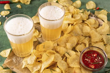 İki bardak light biralı kızarmış patates cipsi, yeşil arka planda.